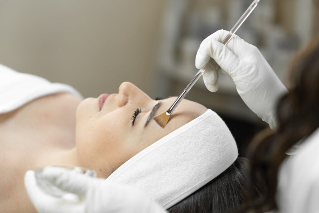 chemical peel formula being applied to a client's face with a brush
